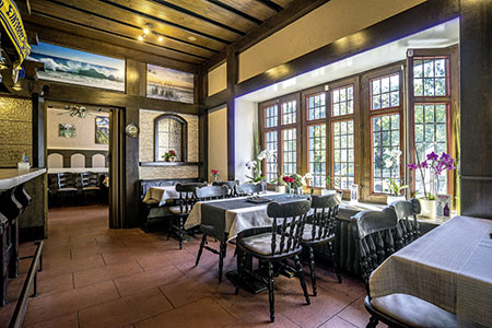 Gastraum mit Sprossenfenstern und eingedeckten Tischen